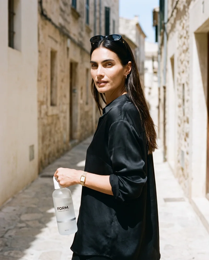 A model holding the FORM. water bottle on a sunlit stone street
